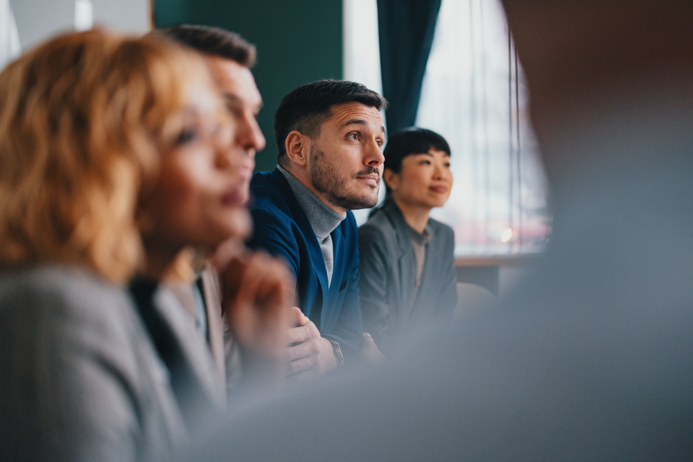 group of leaders sitting at a conference table paying attention to a presentation